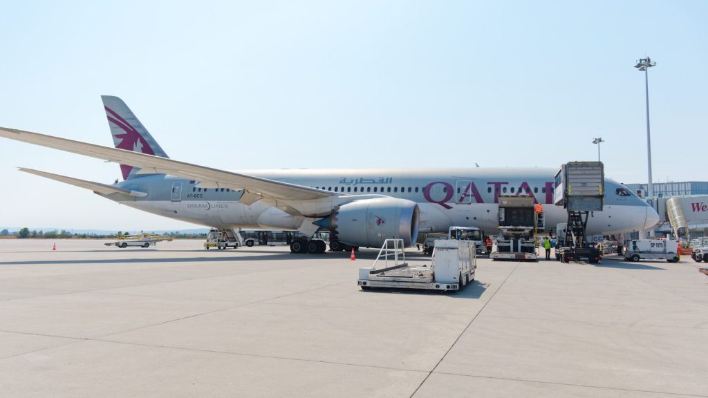 Qatar airways airplane at airport gate with jet bridge