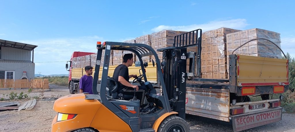 Forklift loading bricks onto a truck outdoors